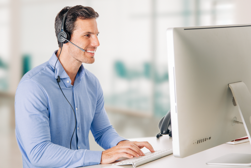 The Best Corded Headsets: man working at computer and wearing a corded headset