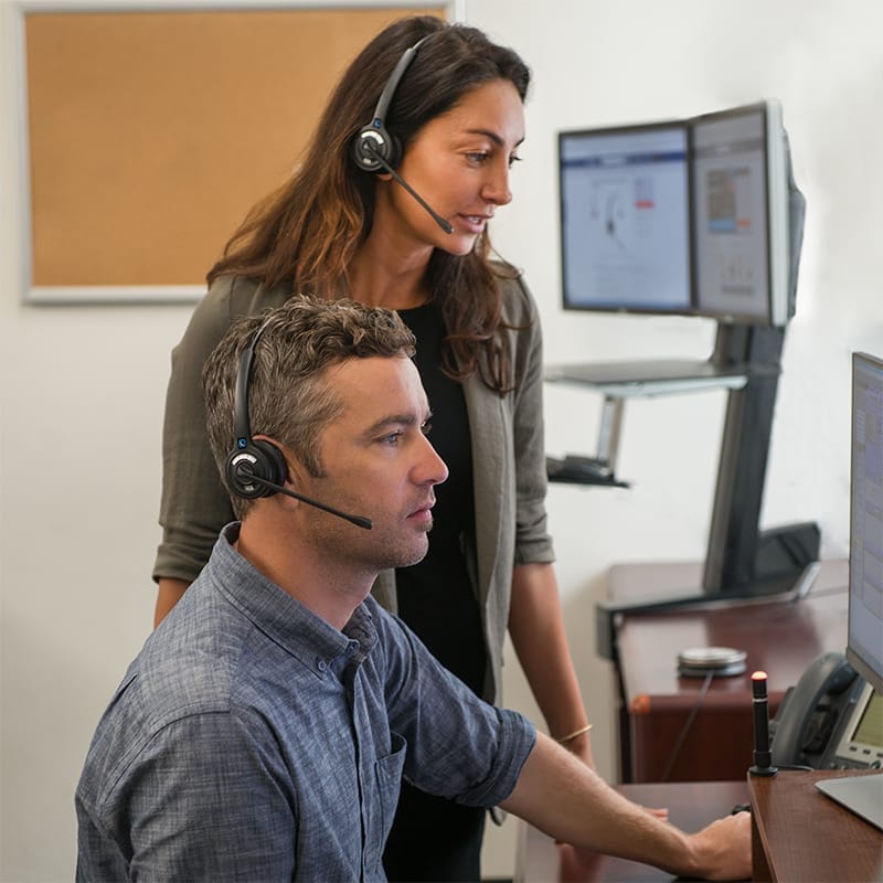 Two workers using LH270 wireless headsets with a computer